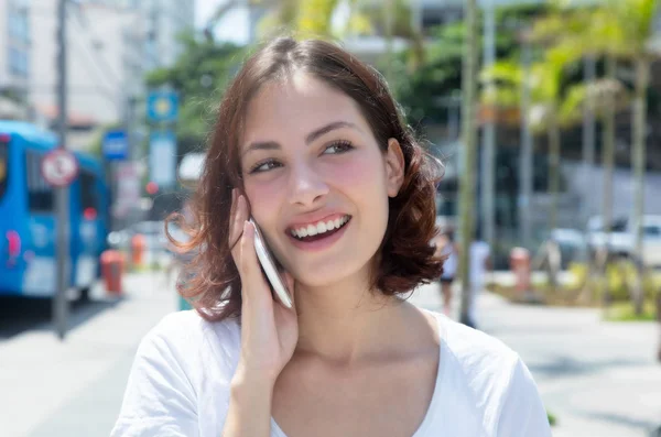 Young caucasian woman laughing at phone