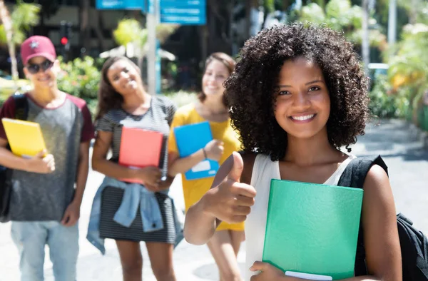 Rire afro-américain femme étudiant montrant pouce avec grou — Photo