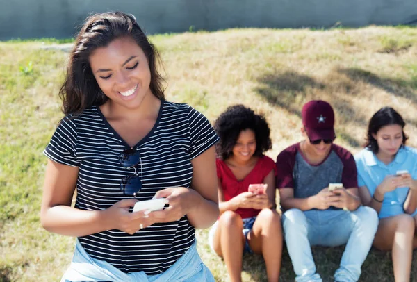 Latin Amerikalı kadın telefon ve uluslararası grup ile gülüyor — Stok fotoğraf