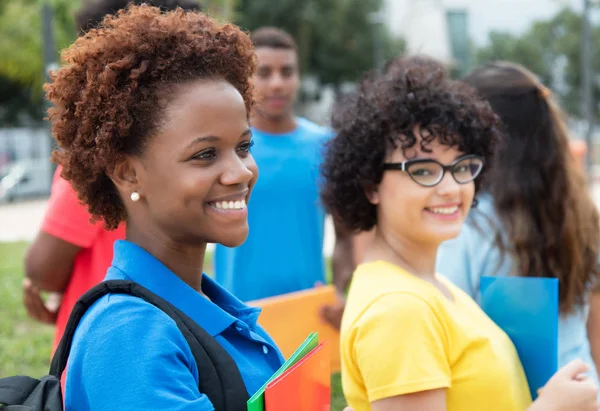 Studente afroamericano con giovane donna caucasica nel campus di — Foto Stock