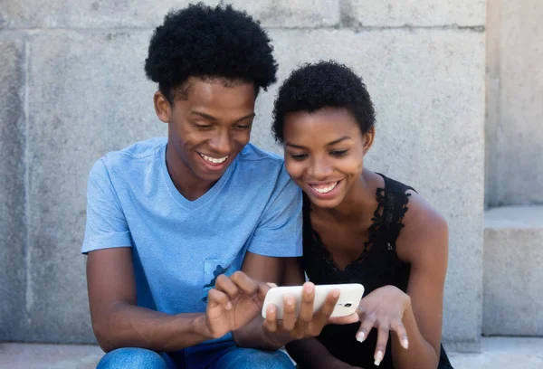 Joyful lachen Afrikaanse Amerikaanse echtpaar telefoon kijken — Stockfoto