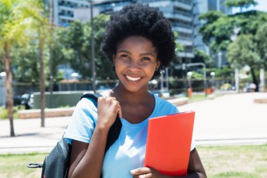 Afro-Amerikan kız öğrencinin üniversite kampüsünde gülüyor