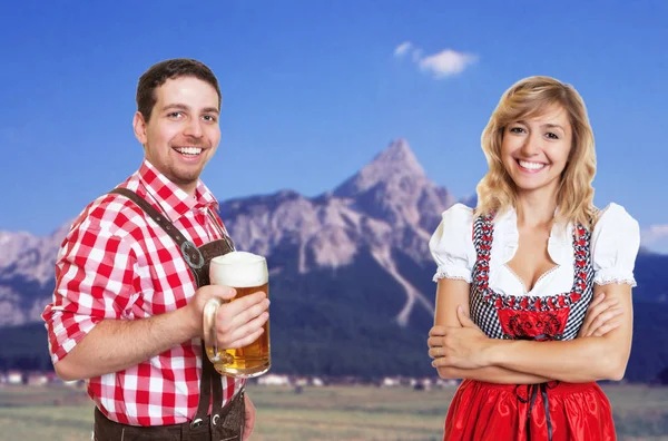 Баварский мужчина с кружкой пива и блондинка с dirndl празднуют — стоковое фото