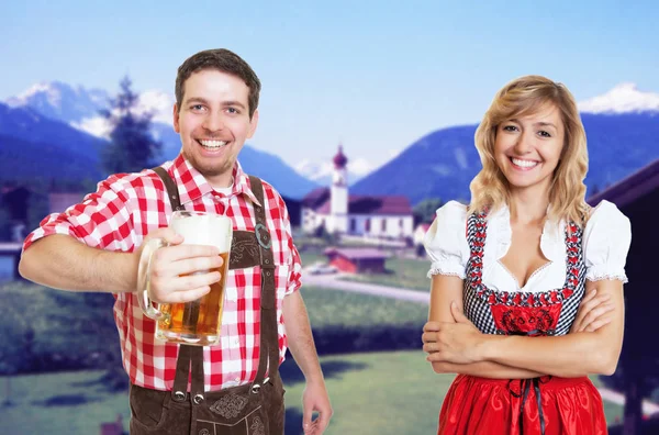 Cheerful bavarian man with leather pants and blonde woman with d — Stock Photo, Image