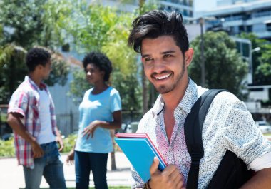 Trendy latin erkek öğrenci arkadaşlarıyla kampüste açık