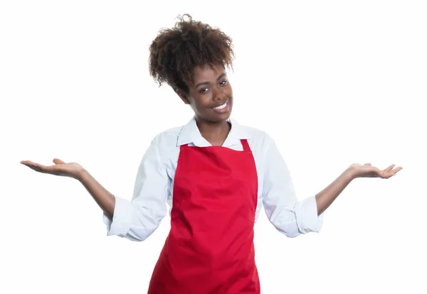 Serveuse afro-américaine riante avec tablier rouge invitant l'invité — Photo