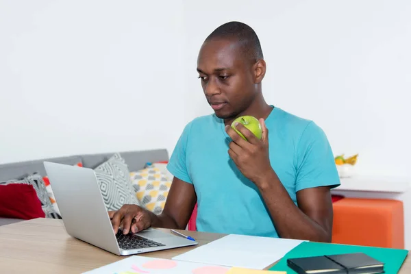 Vuxen afroamerikanska man med laptop äter hälsosam mat på wo — Stockfoto