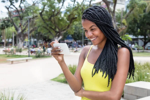 携帯電話でテレビを見ているアフリカ系アメリカ人の若い成人女性 — ストック写真