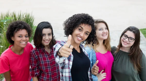 Mulher latino-americana mostrando polegar com grupo de namoradas — Fotografia de Stock