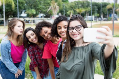 Caucasian woman taking selfie with group of international girlfr