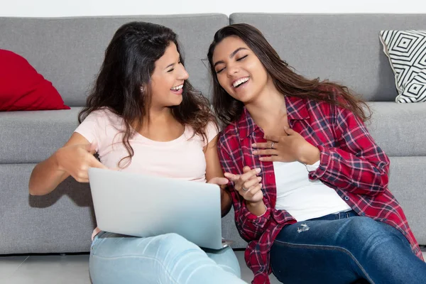 Caucasian woman surfing the net with latin american girlfriend