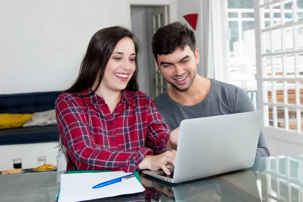 Laughing young couple using computer at home