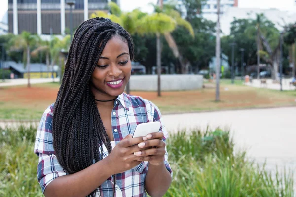 ドレッドヘアの携帯電話でメッセージを送信するとアフリカの女性 — ストック写真