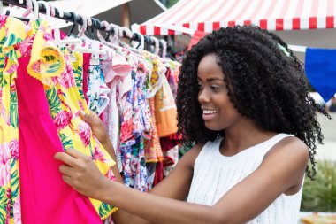 Afrikalı-Amerikalı kadın pazarda renkli giysiler alıyor