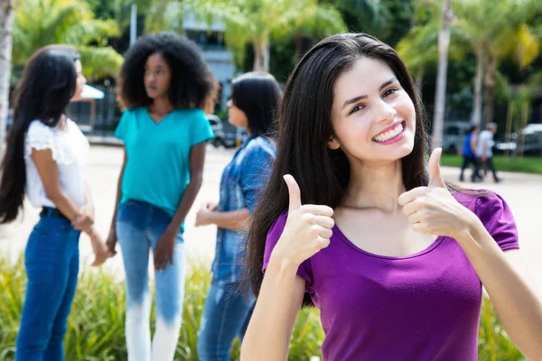 Laughing caucasian woman showing both thumbs with group of girlf — Stock Photo, Image