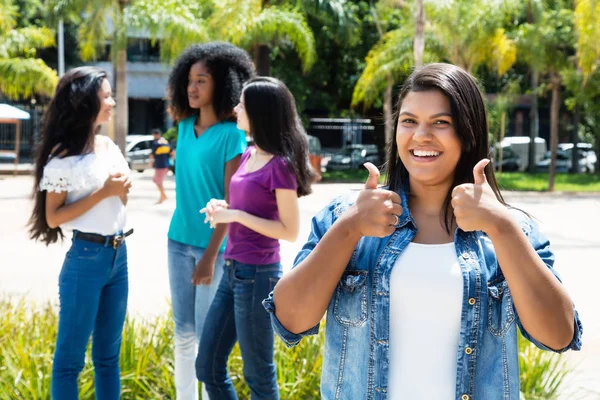 Skrattande infödd latinamerikansk kvinna visar tummen med grupp — Stockfoto