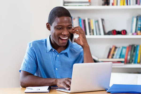 Bonito empresário afro-americano com computador e celular — Fotografia de Stock