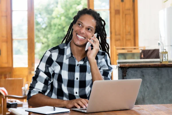 Homem latino-americano feliz com dreadlocks trabalhando em casa — Fotografia de Stock