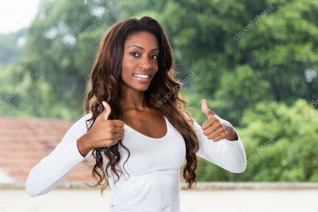 African american woman with long hair showing both thumbs up