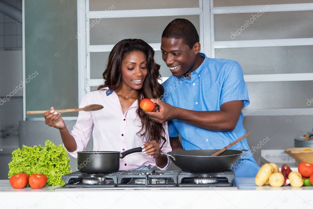 Happy african american love couple cooking at kitchen