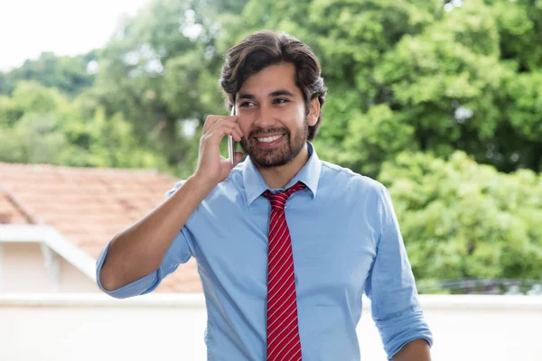 Laughing latin businessman with beard at mobile phone