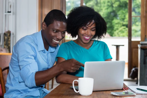 Rindo casal amor afro-americano dentro de casa no computador — Fotografia de Stock