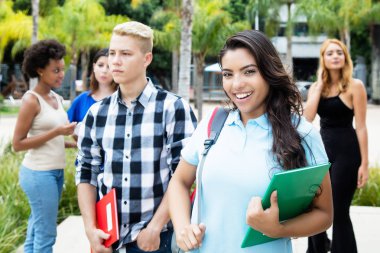 Güzel latin Amerikalı kadın öğrencinin grup uluslararası insan Üniversitesi kampüsünde açık