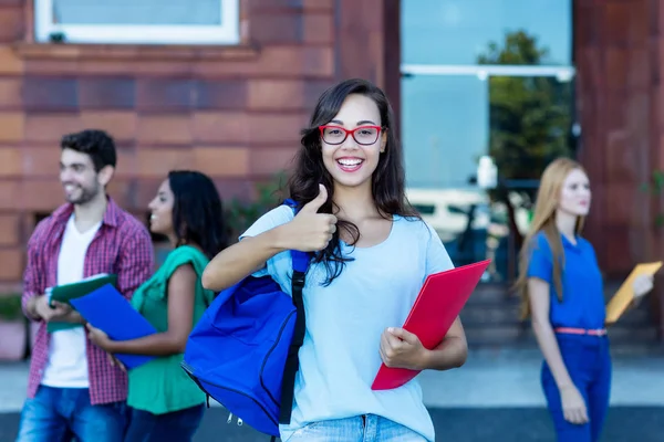 Šťastná nerdy studentka se skupinou mladých dospělých — Stock fotografie