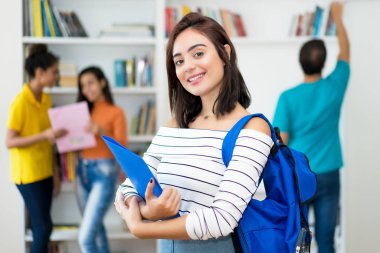 Bir grup öğrenciyle birlikte gülen beyaz bir kız öğrenci.