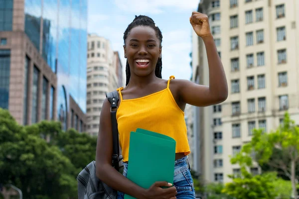 Successful african american young adult female student with dreadlocks outdoor in summer in city