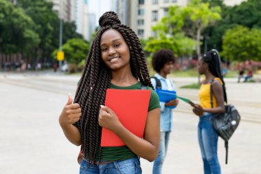 Yazın şehirde harika saç stili olan, gülen Afro-Amerikan bayan öğrenci.