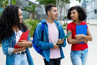 Erkek öğrenci yazın Brezilya ve Arap kız öğrencilerle şehir dışında konuşuyor.
