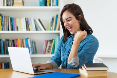 Üniversitede bilgisayar başında çalışan genç kız öğrencilere tezahürat yapıyor.