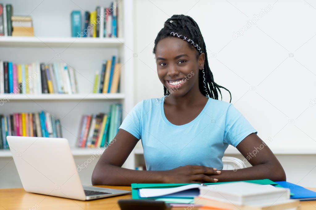 Beautiful african american young adult female student at computer at university