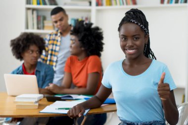 Güzel afro-amerikan genç yetişkin ve bir grup öğrenci üniversite sınıfında.