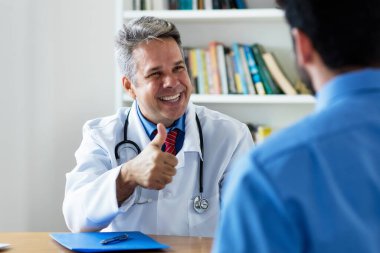 Klinikteki hasta için iyi haberleri olan olgun bir doktor.