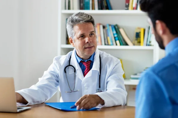 Mature Doctor Talking Patient Symptoms Cornavirus Clinic — Stock Photo, Image