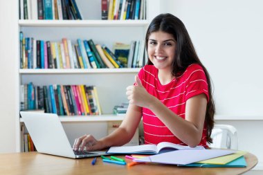 Güzel İspanyol kız öğrenci evde bilgisayar kullanarak online dil öğreniyor.