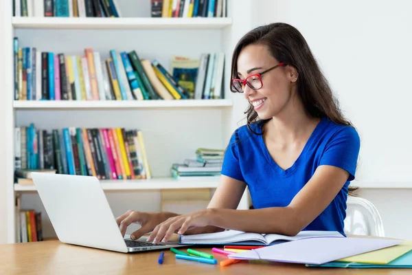Laughing nerdy female student learning language online using computer at home