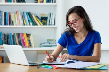 İnek kız öğrenci dil öğreniyor ve evdeki bilgisayar mezuniyetine hazırlanıyor.