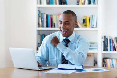 Amigoluk yapan Afro-Amerikan iş adamı evde kalır ve ofisteki bilgisayarın başında çalışır.