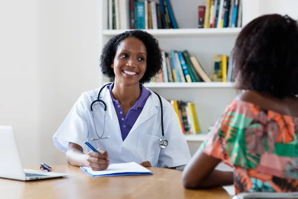 Olgun Afro-Amerikan kadın doktor hastanedeki hastalara iyileşme hakkında konuşuyor.