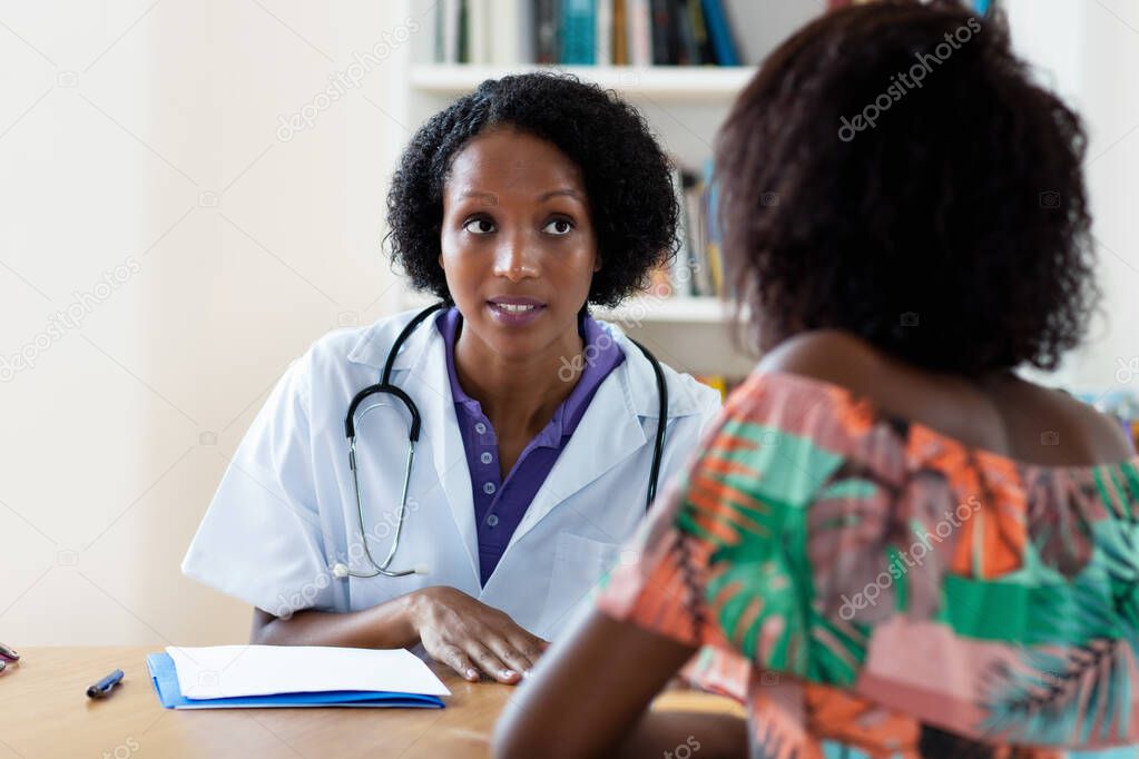 Mature african american female doctor explaining flu and coronavirus symptoms to patient at hospital
