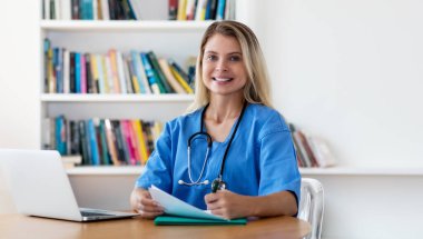 Hastanede ya da klinikte gülen sarışın hemşire ya da doktor.