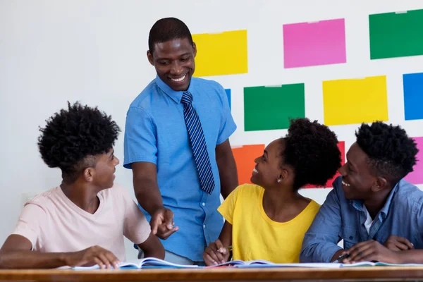 African american male teacher talking with students at classroom of school