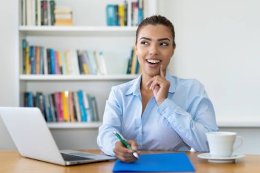 Ofisteki masada bilgisayarlı Latin Amerikalı iş kadınını düşünmek ve hayal etmek.