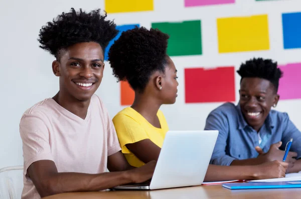 African american male student at computer with group of students at classroom of university or college