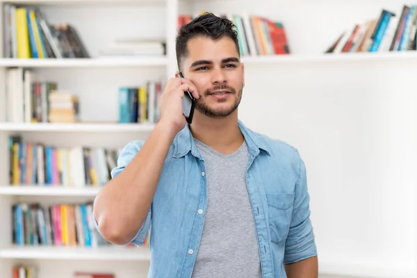 Hispanic hipster man in quarantine talking at mobile phone indoors at home