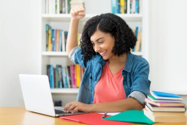 Güney Amerikalı kız öğrenci evdeki karantinada bilgisayar alışverişi yapıyor.