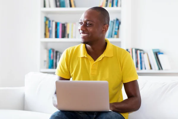 Laughing african american mature adult man in quarantine working at computer indoors at home